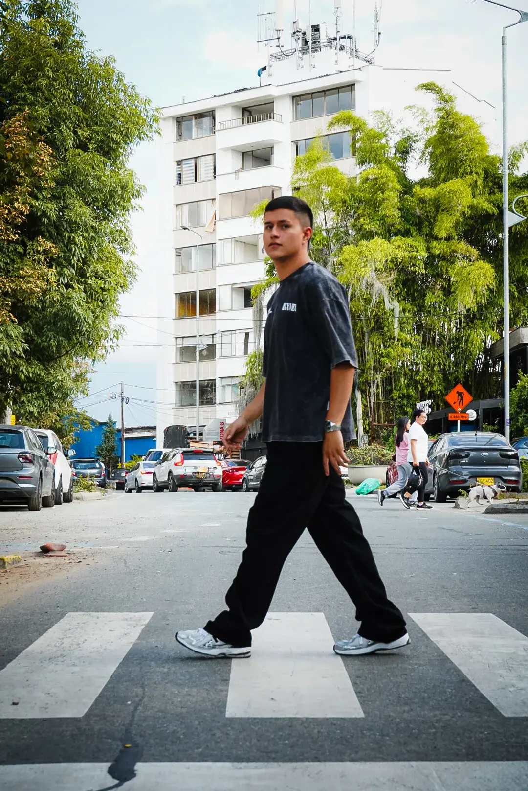 Modelo cruzando la calle con la Camisa Ascendant Boxyfit y pantalón negro