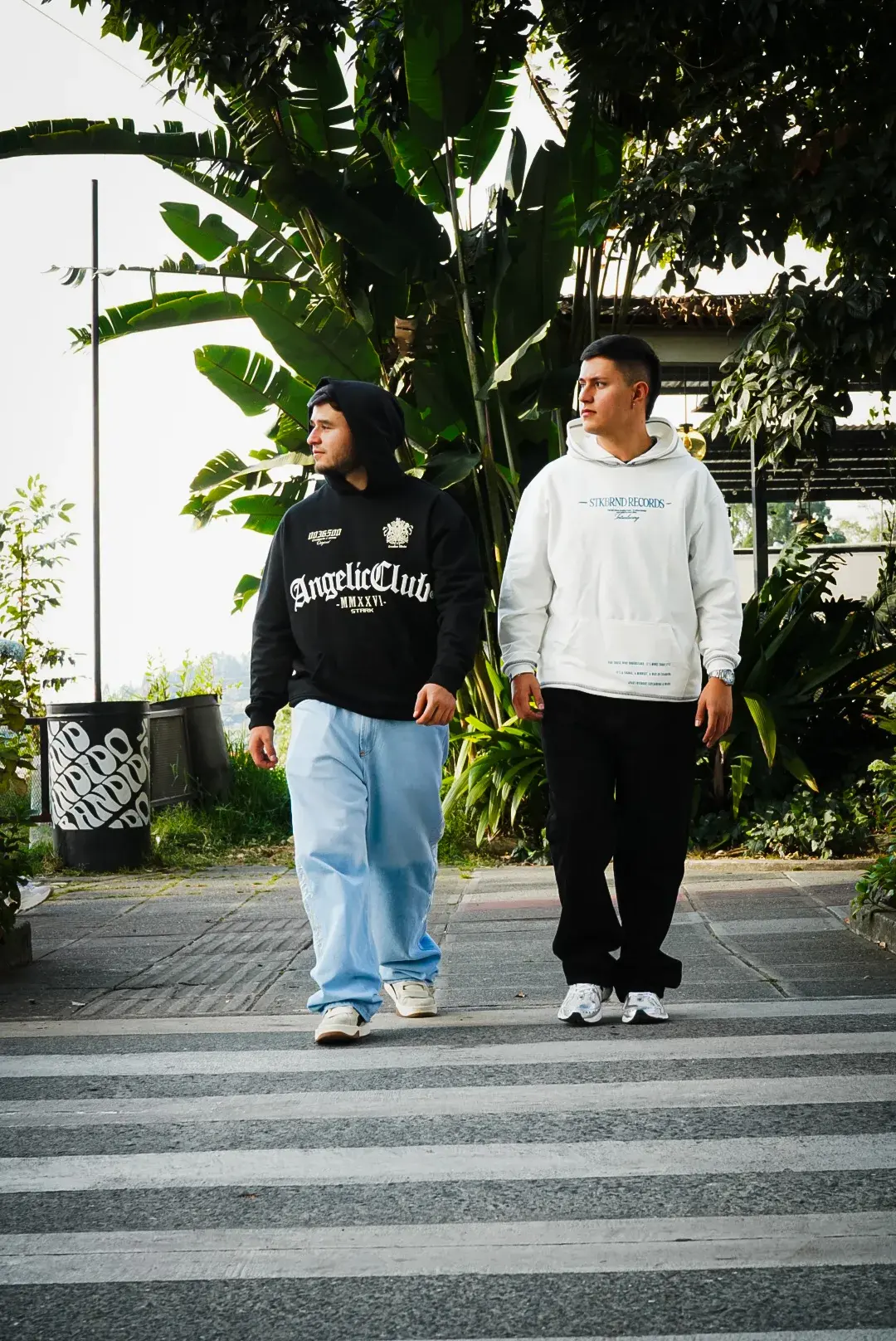 Dos modelos cruzando un paso peatonal con los busos Angelic Club y Crudo Records